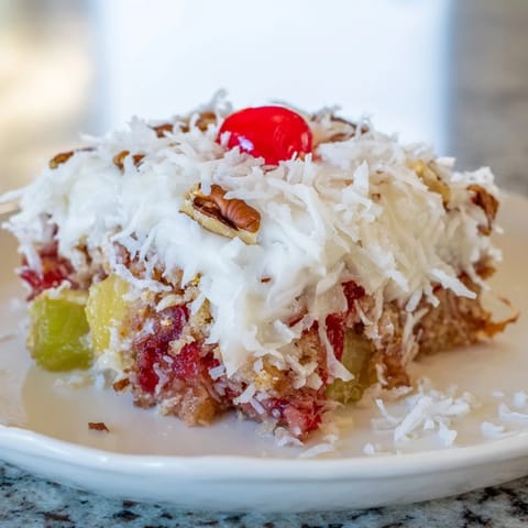 This fruit cocktail cake image shows a sliced dessert with a lovely, sweet fruit filling and frosting.