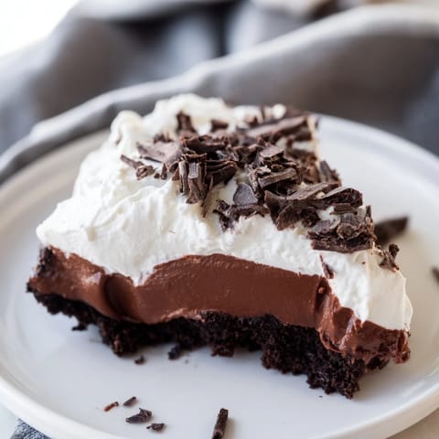 A slice of Mississippi Mud Pie showcases layers of rich chocolate pudding and fluffy whipped cream.