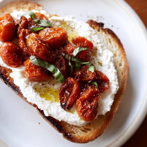 Whipped ricotta spread over rustic sourdough, topped with caramelized cherry tomatoes, lemon zest, and flaky sea salt for a bright Mediterranean bite.