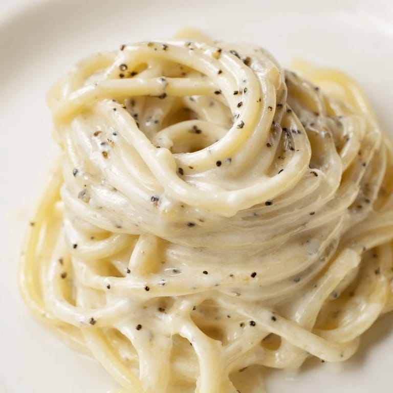 Steaming bowl of Spaghetti Cacio e Pepe served with extra grated cheese and a glass of crisp white wine.