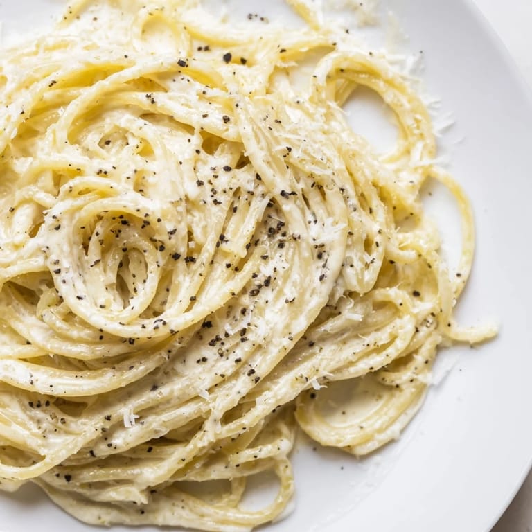 Skillet of Spaghetti Cacio e Pepe tossed with pepper flakes, ready to be served for an Italian dinner.