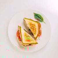 Golden, crispy sourdough slices are layered with fresh mozzarella, ripe tomato rounds, and aromatic basil pesto, creating a melted Caprese Pesto Grilled Cheese sandwich.
